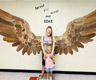 Two pose for photo with eagle wings